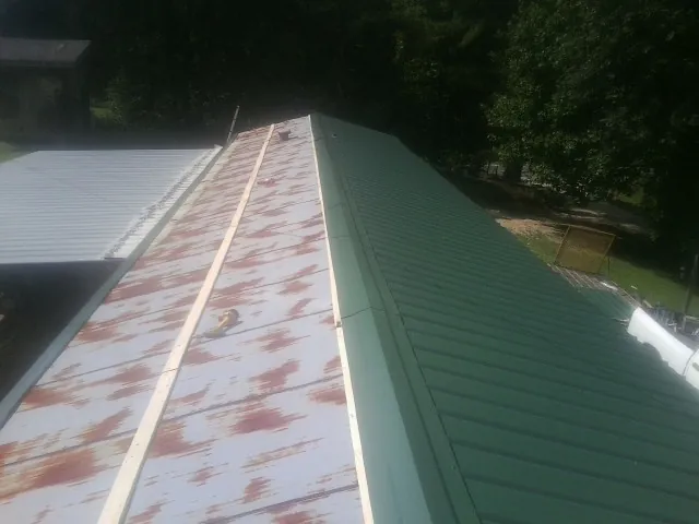 Old rusted panels beside newly installed green metal roofing — Wind Damage Roof Repair by Roofing Brothers in Deep River