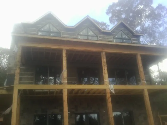 Dormers and porch framing on a large log home under construction — Roof Coating work by our crew in Deep River