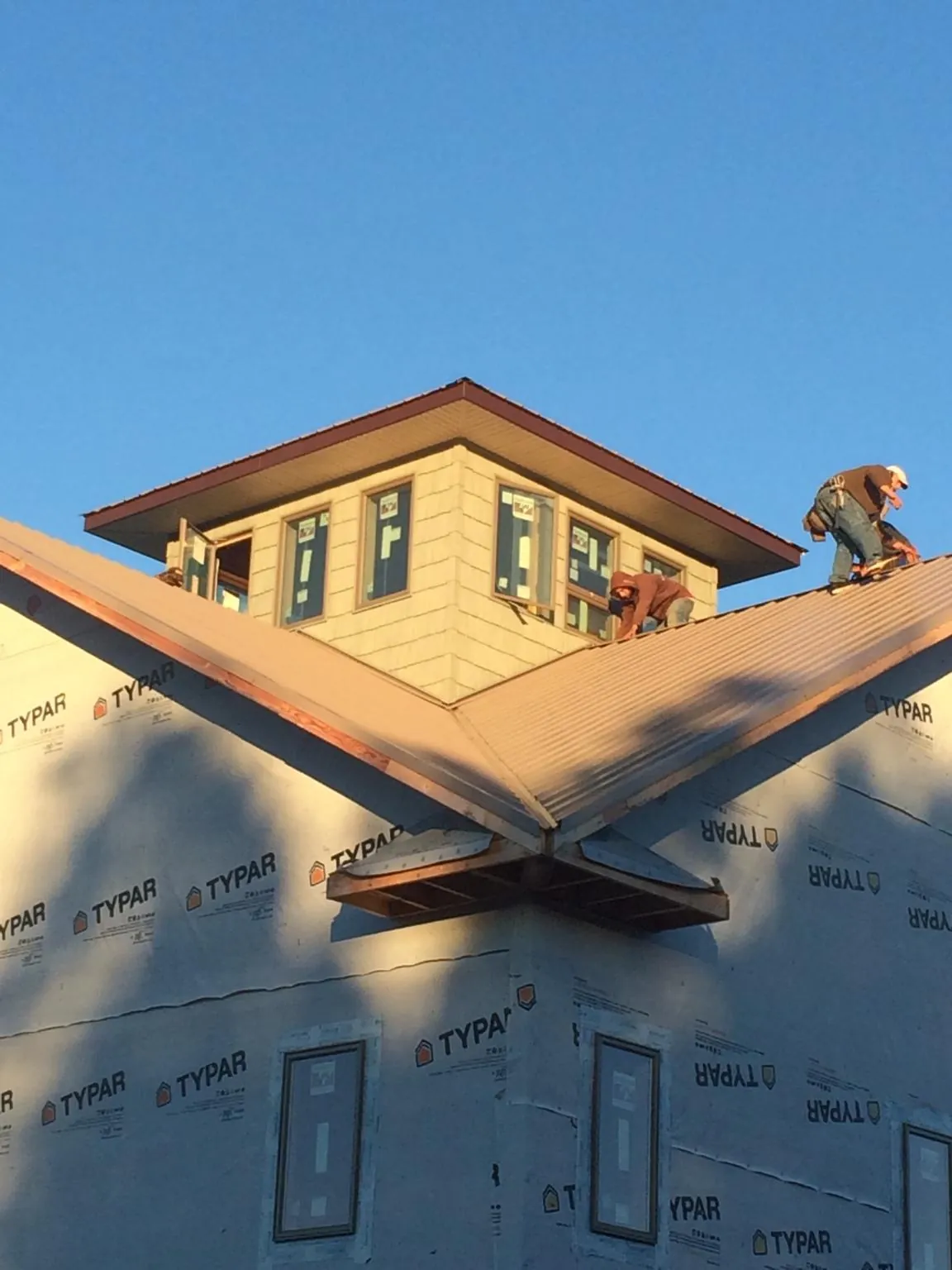 Roofers working around a rooftop cupola on a new metal roof at sunset — Roof Waterproofing in Deep River by Roofing Brothers